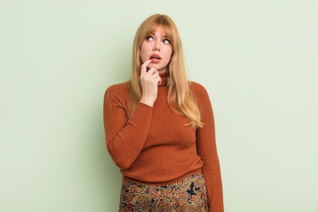 Redhead pretty woman with surprised nervous worried or frightened look looking to the side towards copy space