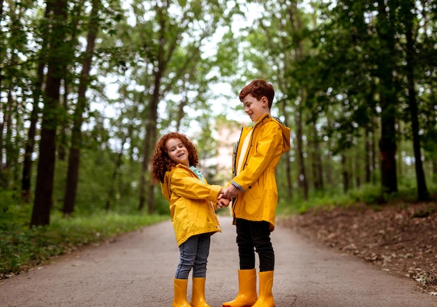 Redhead siblings in yellow raincoats in park