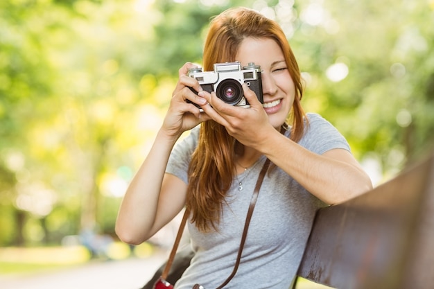 Redhead che si siede sul banco che cattura una foto