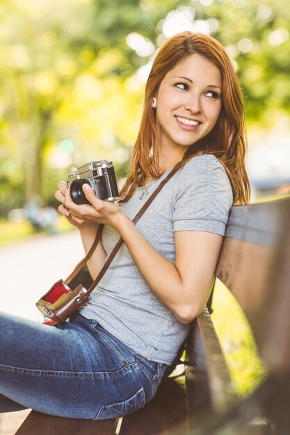 彼女のカメラを使ってベンチに座っている赤毛