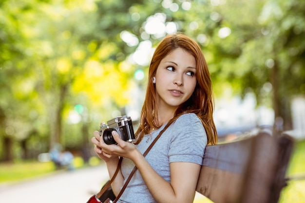 彼女のカメラを使ってベンチに座っている赤毛