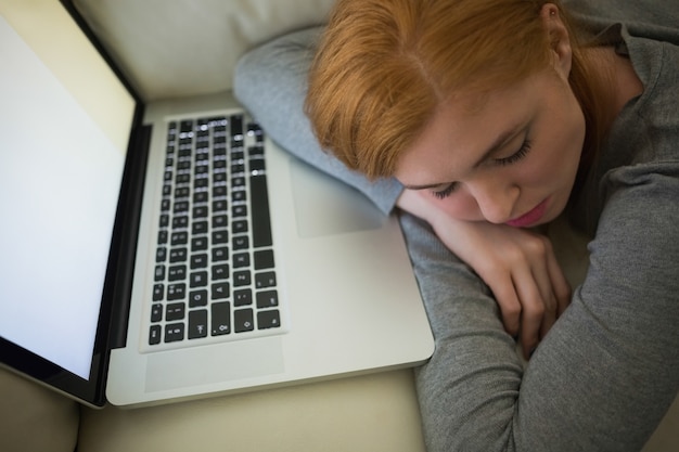 Redhead sleeping on the couch with her laptop 