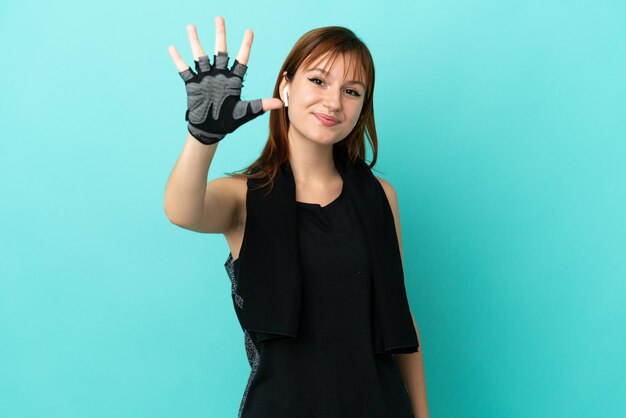 Redhead sport girl isolated on blue background counting five with fingers