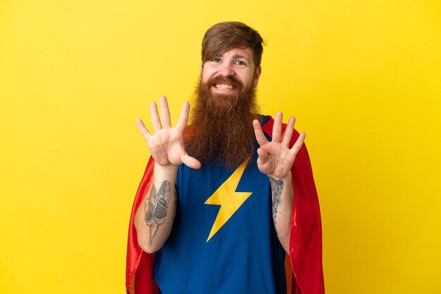 Redhead Super Hero man isolated on yellow background counting nine with fingers