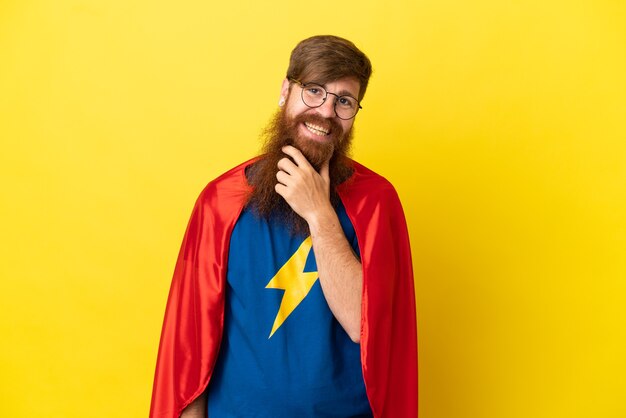 Redhead Super Hero man isolated on yellow background with glasses and smiling