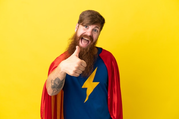 Redhead Super Hero man isolated on yellow background with thumbs up because something good has happened