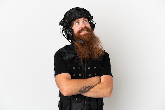 Redhead SWAT isolated on white background looking up while smiling