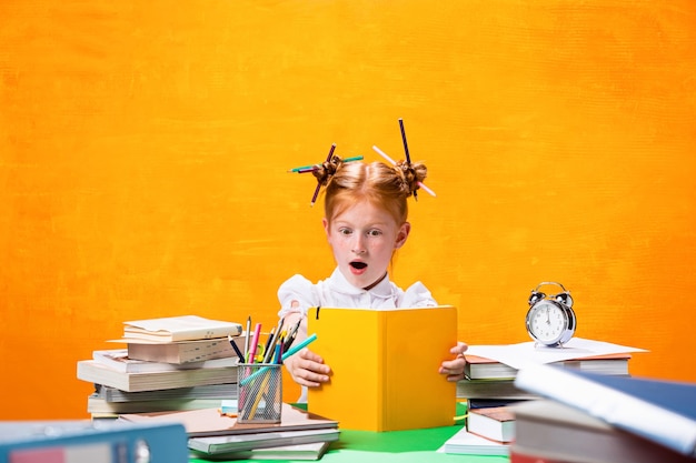 The Redhead teen girl with lot of books at home. Studio shot