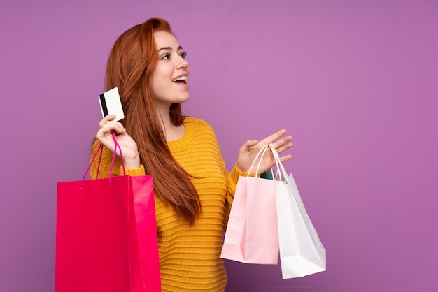 ショッピングバッグとクレジットカードを保持している赤毛の10代女性
