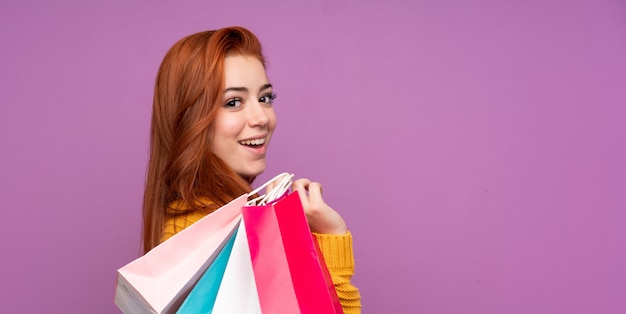 赤毛の10代女性の買い物袋を押しながら笑みを浮かべて