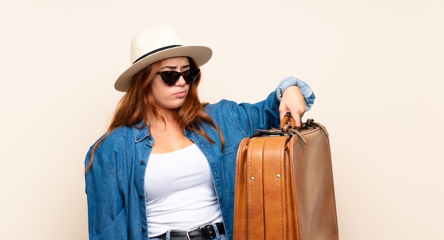 Рыжая путешественница с чемоданом с грустным выражением лица