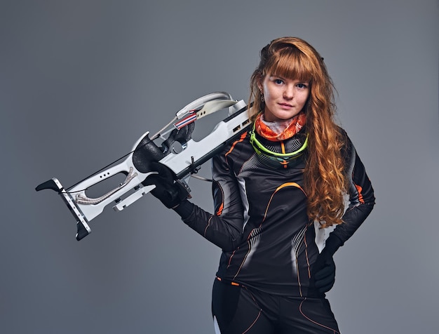 Redhead vrouwelijke Biathlon kampioen gericht met een competitieve pistool in een studio over grijze achtergrond. Redhead vrouwelijke Biathlon kampioen gericht met een competitieve pistool in een studio over grijze achtergrond.