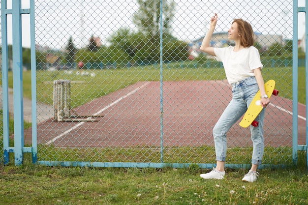 Redhead white girl with skateboard near fence