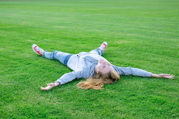 写真 赤毛の白い若い女性が横になっていると、サッカー場の芝生の上でラクラク。