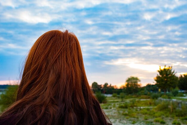 Photo redhead woman against cloudy sky during sunset