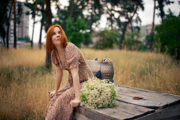 Redhead woman of forty years with a large bouquet of wildflowers in summer in nature