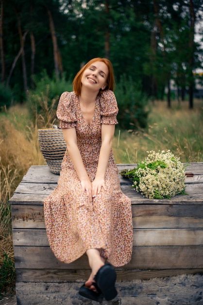 Redhead woman of forty years with a large bouquet of wildflowers in summer in nature