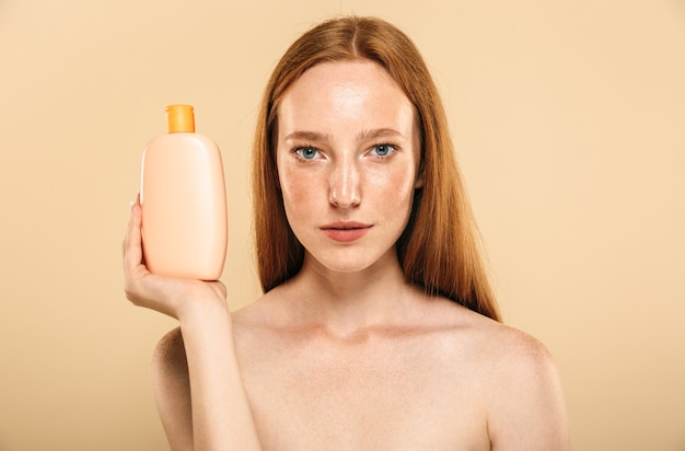 Redhead woman holding cream for skin care.