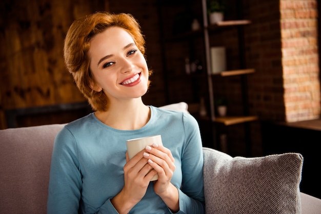 Redhead woman posing on the sofa at home