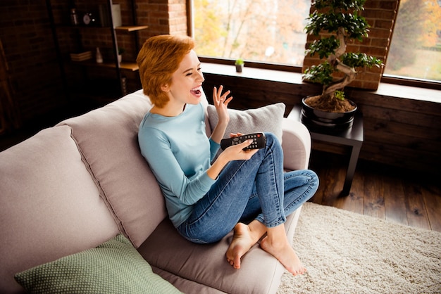 Redhead woman posing on the sofa at home