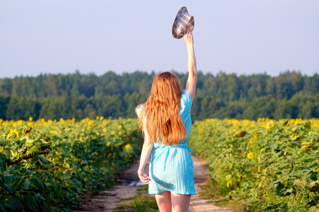 Redhead woman walking among sunflower field