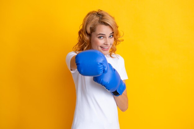 Redhead woman with boxing gloves punching isolated on yellow background