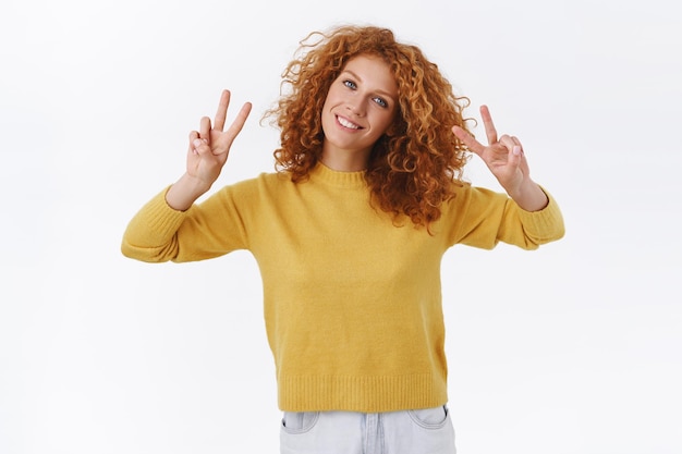 redhead woman with curly hair, smiling happy and showing peace signs