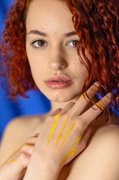 Рыжая женщина с руками, выкрашенными в желтый цвет