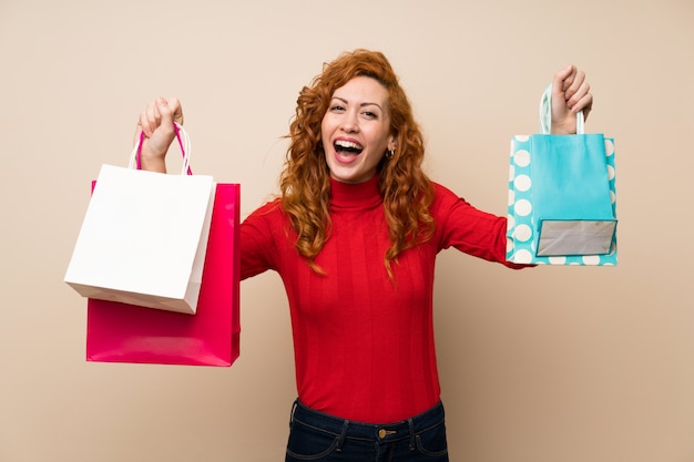 Redhead woman with turtleneck sweater holding a lot of shopping bags