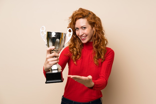 Redhead woman with turtleneck sweater holding a trophy