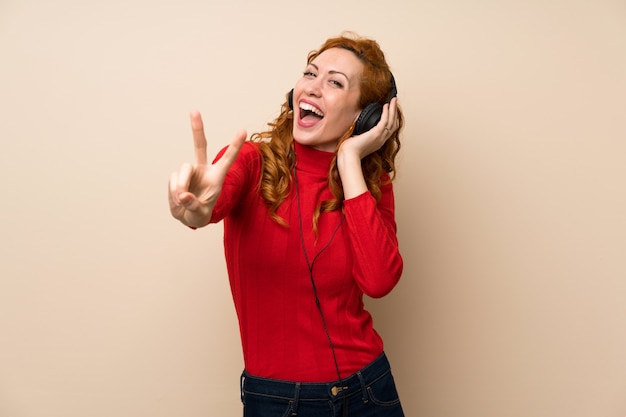 Redhead woman with turtleneck sweater listening to music with headphones