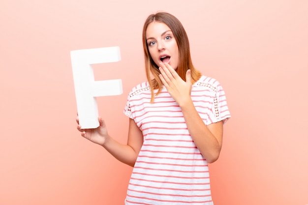 redhead young girl in a T-shirt holding the letter f