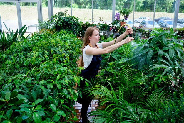 Redhead young woman in plant market pouring plants