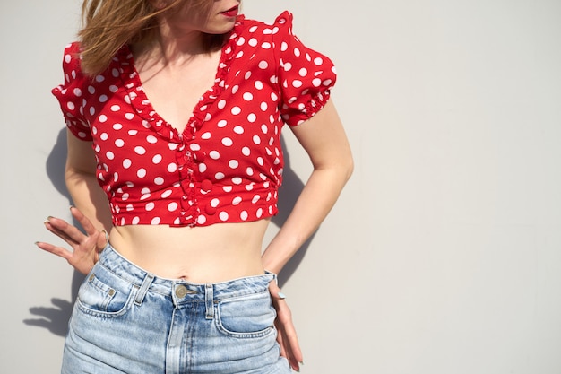 Redhead young woman in red blouse in polka-dot pattern