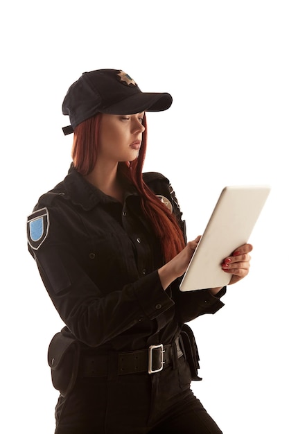 빨간 머리 여성 경찰관이 흰색 배경에 격리된 카메라를 위해 포즈를 취하고 있다
