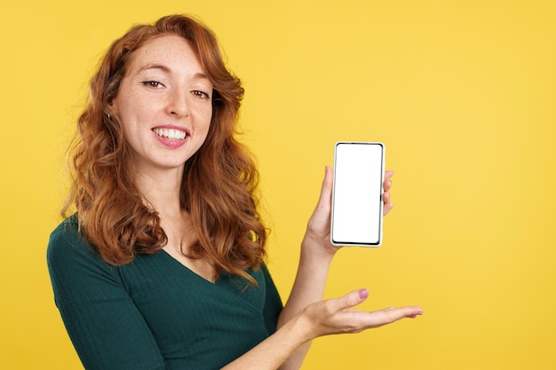 Redheaded happy woman presenting a mobile with a blank screen
