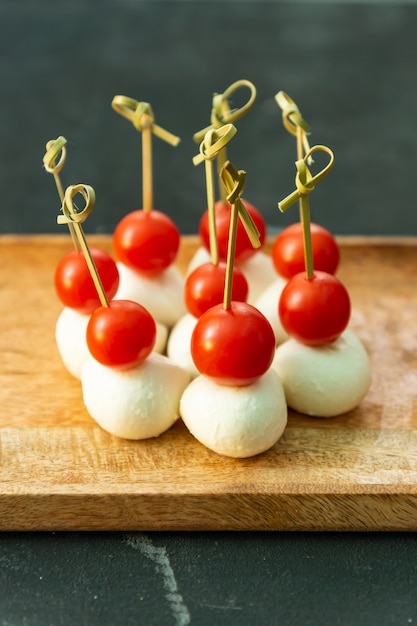 Reeks heerlijke canapeetjes met omhoog tomaten en mozzarella op houten plaat.