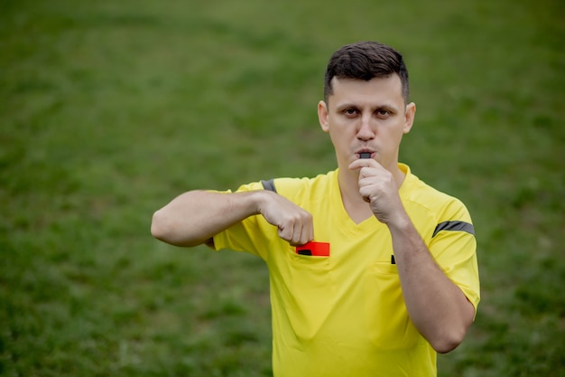 Arbitro che mostra un cartellino rosso a un calciatore dispiaciuto durante il gioco. concetto di sport, violazione delle regole, questioni controverse, superamento degli ostacoli.