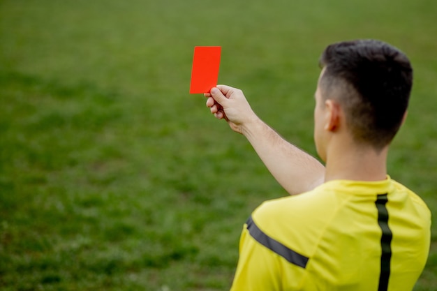 Arbitro che mostra un cartellino rosso a un giocatore di calcio o di calcio scontento durante il gioco. concetto di sport, violazione delle regole, questioni controverse, superamento di ostacoli.