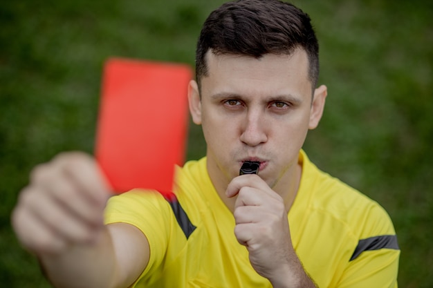 Foto arbitro che mostra un cartellino rosso a un calciatore dispiaciuto durante il gioco