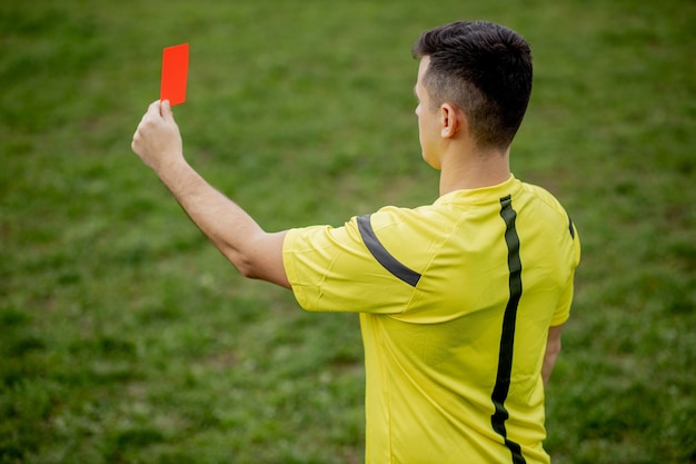 Photo referee showing a red card to a displeased football or soccer player while gaming.