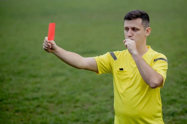 Foto arbitro che mostra un cartellino rosso a un calciatore dispiaciuto durante il gioco.