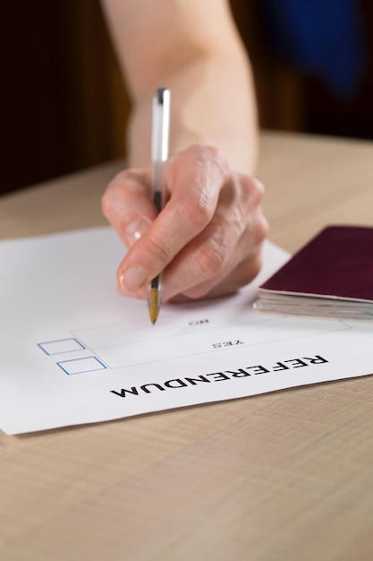 Referendum stembiljet, zwarte pen en paspoort op tafel. Detailopname