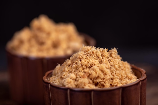 The refined meat floss is in the cup in the dark background