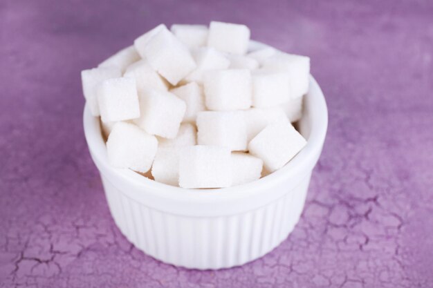 Refined sugar in bowl on color wooden background