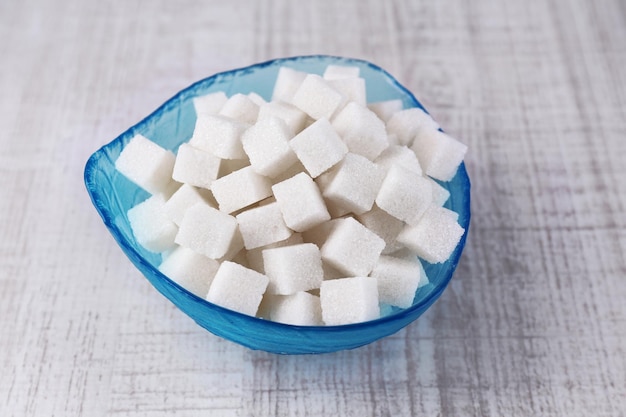 Refined sugar in color bowl on wooden background