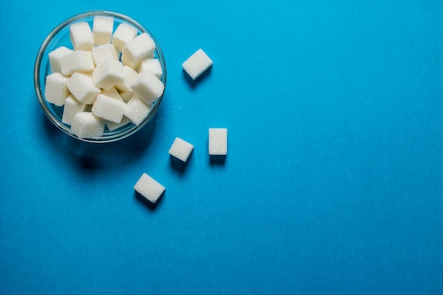 Refined sugar in the Cup. On a blue table.