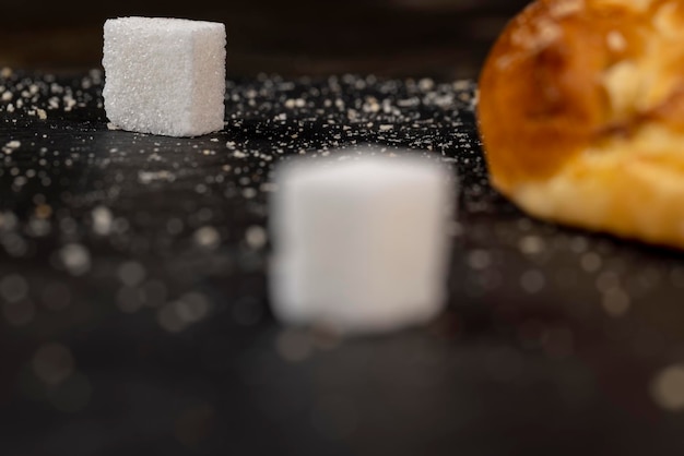 사진 검정 슬레이트 보드에 있는 정제된 설탕 조각은 사탕무에서 나온 설탕 조각을 닫습니다.
