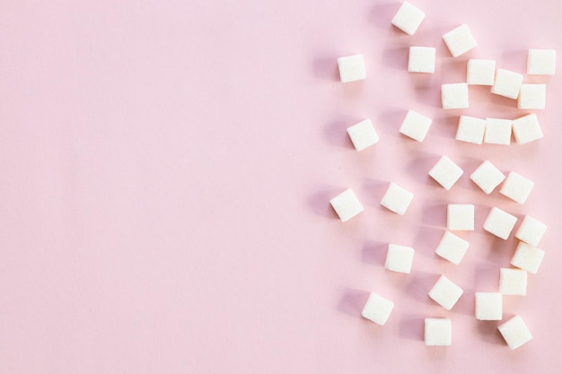 Refined sugar on pink backgroundCubes of sweet and white sugar