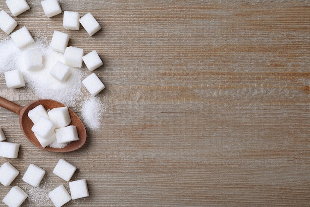 Refined sugar on wooden table flat lay Space for text